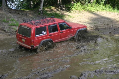 2003 Jeep TJ - Jeep Cherokee XJ navigating a muddy trail, wheels deep in the mire.