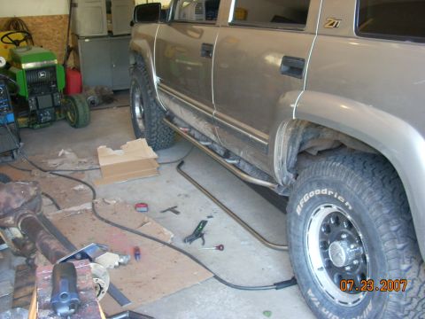 2000 Chevrolet Tahoe - An SUV is parked in a garage, with new running boards being installed. A lawn tractor is also present.