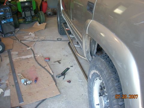 2000 Chevrolet Tahoe - Custom rock sliders are being installed on the side of a 2000 Chevrolet Tahoe in a garage.