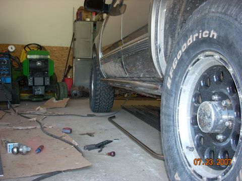 2000 Chevrolet Tahoe - An SUV is parked in a garage next to a lawn tractor, with tools and parts scattered on the floor.