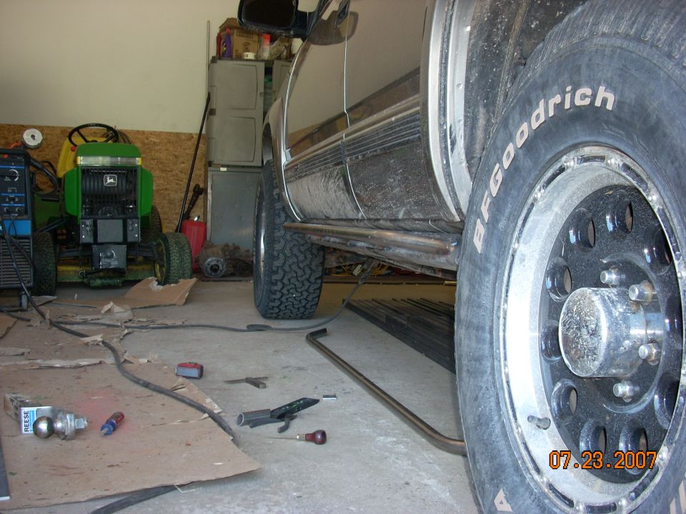 Side view of an SUV in a garage next to a John Deere lawn tractor. BFGoodrich tires visible