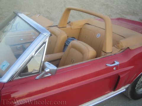 1990 Ford Bronco - red vintage convertible with a tan leather interior sits with its top down, viewed over the driver's door.