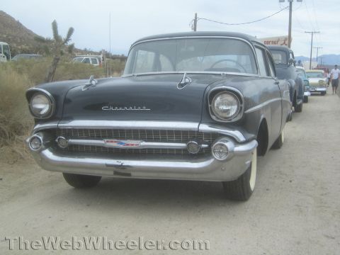 1990 Ford Bronco - Front three-quarter view of a dark 1957 Chevrolet sedan showing its chrome grille and 'Chevrolet' hood script.