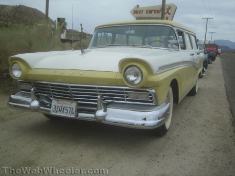 1990 Ford Bronco - two-tone yellow and white 1957 Ford station wagon parked on a desert road with a California plate and chrome grille.