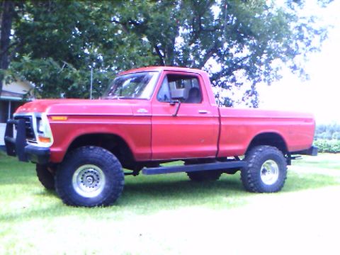 1979 Ford F-150 - Side view of a red 1979 Ford F-150 pickup truck with lifted suspension and off-road tires.