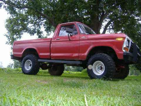 1979 Ford F-150 - A red 1979 Ford F-150 pickup truck is shown from a three-quarter front angle, parked outdoors.