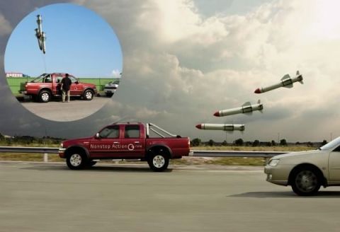 1978 Ford Mustang II - A red pickup truck appears to be evading missiles while a silver sedan drives alongside on a cloudy day.