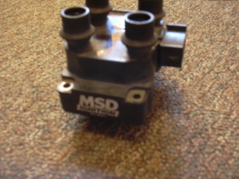 1997 Ford Crown Victoria - A black MSD ignition coil sits on a carpeted surface.