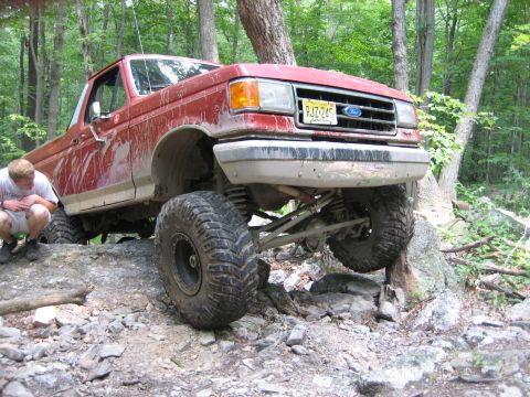 1990 Ford Bronco - This lifted 1990 Ford Bronco is shown off-roading over rocks and trees.