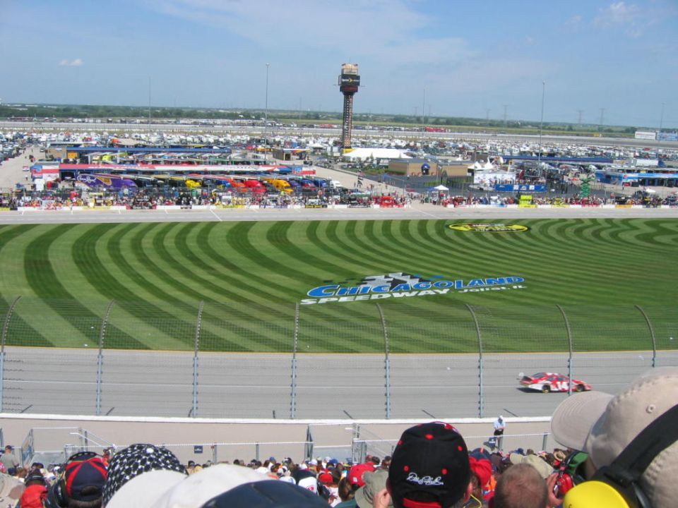 Chicagoland Speedway with race cars on track and parking lot full of vehicles