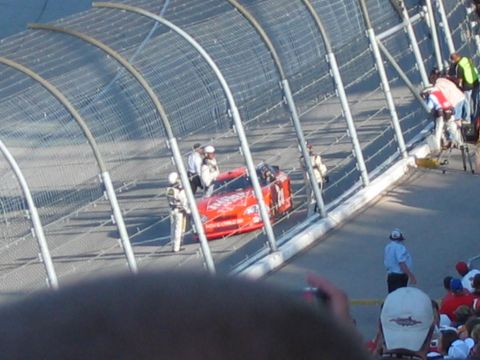1985 Ford Crown Victoria LTD - A race car is being attended to by crew members on the track at a NASCAR event.
