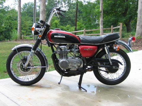 1985 Ford Crown Victoria LTD - A vintage Honda motorcycle with a two-tone red and black fuel tank is shown parked outdoors.