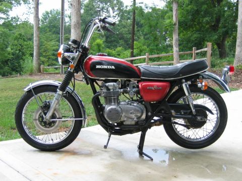 1985 Ford Crown Victoria LTD - A side view of a red and black Honda motorcycle with chrome accents, parked outdoors on a paved surface.