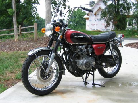 1985 Ford Crown Victoria LTD - A vintage red and black Honda motorcycle is shown from a three-quarter front view, parked outdoors on a paved surface.