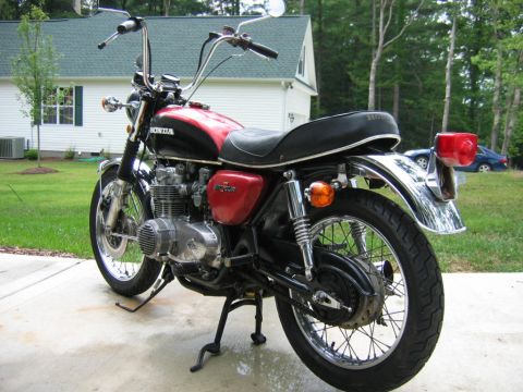 1985 Ford Crown Victoria LTD - A black and red Honda motorcycle is parked on a concrete driveway in front of a house.