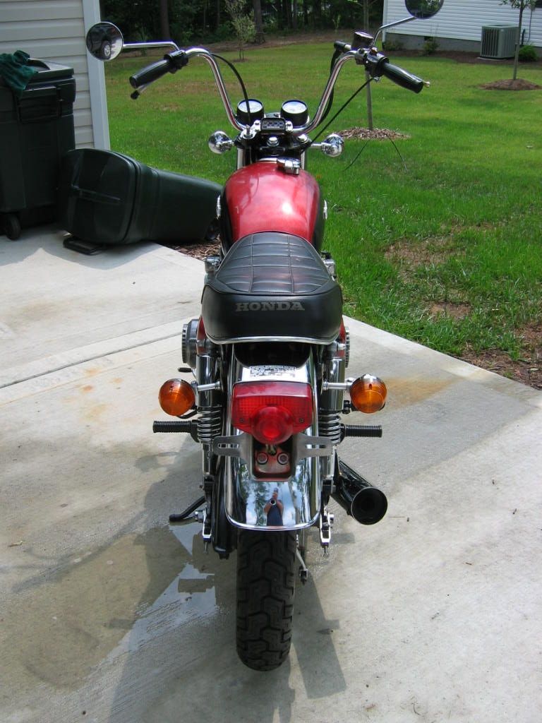 Red Honda motorcycle rear view with black seat and chrome accents