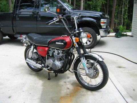 1985 Ford Crown Victoria LTD - A red and black Honda motorcycle is parked on a concrete driveway in front of a black pickup truck.