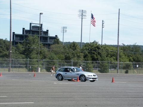 2001 Mercury Grand Marquis - Silver BMW M coupe navigates an autocross course with orange cones and an American flag in the background.