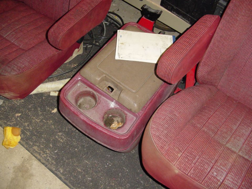 Two red cloth bucket seats with a center console cupholder organizer between them