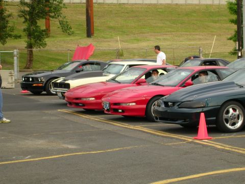 1996 Ford Probe - A lineup of sports cars, including Mustangs and Ford Probes, are parked in a lot with orange cones.