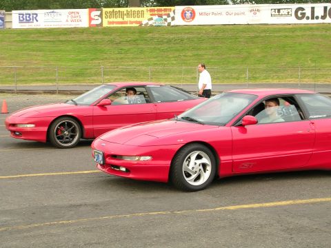 1996 Ford Probe - Two red Ford Probe cars are lined up on a race track, possibly for a drag race.