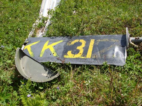 2000 Ford E350 - A damaged part with yellow lettering 'KK 31' lies on the grass.
