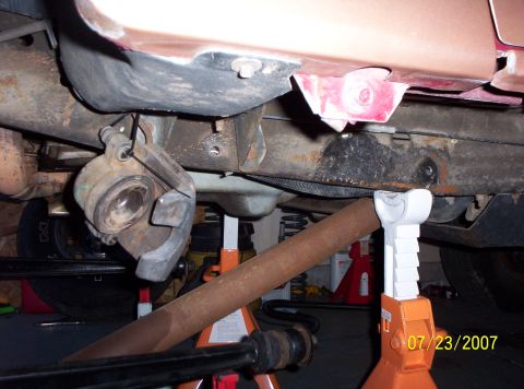 1995 Ford Bronco - Vehicle undercarriage with brake caliper and suspension parts visible, supported by jack stands.