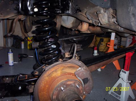 1995 Ford Bronco - Underneath view of a vehicle's suspension system, showing a large coil spring and brake components.