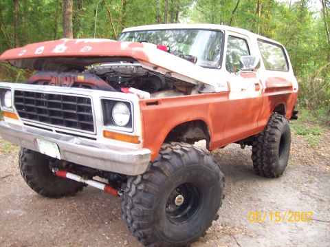 1978 Ford Bronco - This lifted 1978 Ford Bronco, painted in orange and white, sits with its hood open, revealing the engine bay.