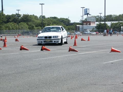 2001 Mercury Grand Marquis - White BMW E36 M3 navigates an autocross course on a sunny day.