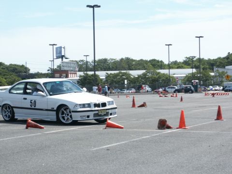 2001 Mercury Grand Marquis - A white BMW E36 coupe is set up for an autocross event with cones marking the course.