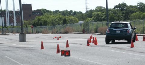 2001 Mercury Grand Marquis - A Mini Cooper drives through an autocross course with cones set up in a parking lot.