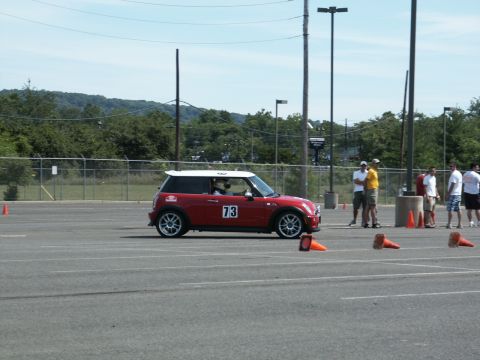 2001 Mercury Grand Marquis - A red Mini Cooper with a white roof and the number 73 on its door navigates a course marked by orange cones on a sunny day.