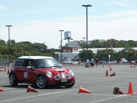 2001 Mercury Grand Marquis - A red Mini Cooper with a white roof and racing number 73 navigates an autocross course on a bright, sunny day.