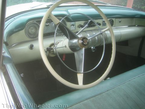 1990 Ford Bronco - Interior of a 1950s Buick showing a large white two-spoke steering wheel, teal and chrome dashboard and gauges.