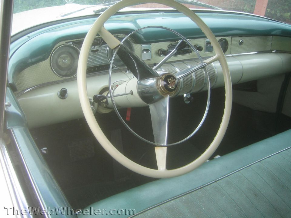 Interior of a 1950s Buick with white steering wheel and teal dash