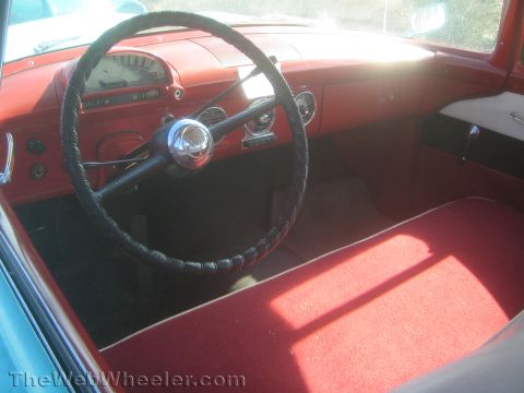 1990 Ford Bronco - red interior of a classic car, with a thin black steering wheel, painted metal dashboard, round gauges and a carpeted floor.