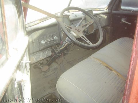 1990 Ford Bronco - dust-covered interior of an old truck, with a worn steering wheel, painted dash, radio and a faded bench seat.
