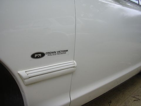 1997 Ford Crown Victoria - Close-up of a white Crown Victoria Police Package fender emblem.