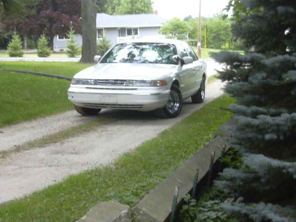 1997 Ford Crown Victoria parked on a gravel driveway in front of a house