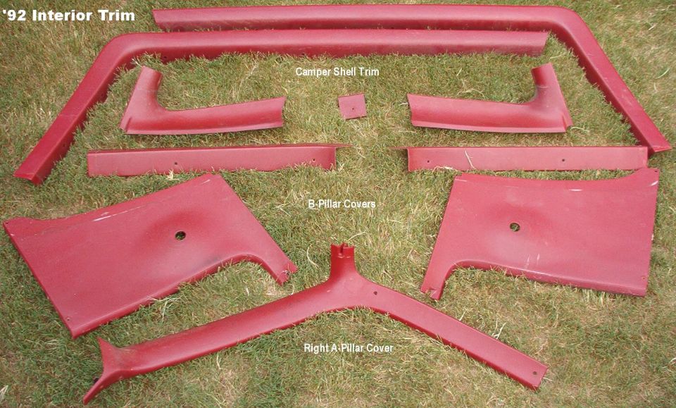 Red Bronco interior trim panels laid on grass, labeled