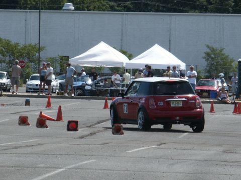 2001 Mercury Grand Marquis - Red Mini Cooper navigates an autocross course with other vehicles and spectators present.