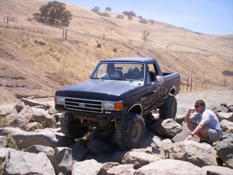 1989 Ford Bronco - A black 1987 Ford Bronco navigates a rocky trail in a dry, hilly landscape.