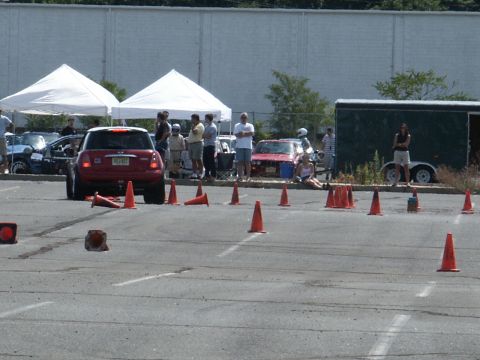 2001 Mercury Grand Marquis - A red Mini Cooper navigates an autocross course marked by orange cones, with spectators and other vehicles in the background.