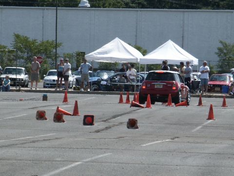 2001 Mercury Grand Marquis - A red Mini Cooper navigates a cone course during an event, with spectators and other vehicles present.