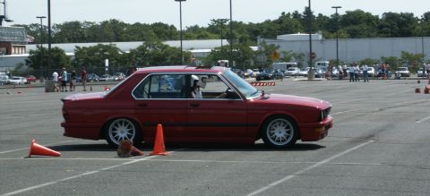 2001 Mercury Grand Marquis - A red BMW sedan navigates a course marked by orange cones in a parking lot.