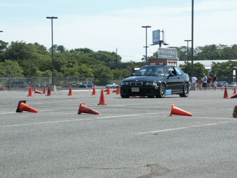 2001 Mercury Grand Marquis - A black BMW M3 coupe is seen on a race track during an autocross event, maneuvering around orange cones.