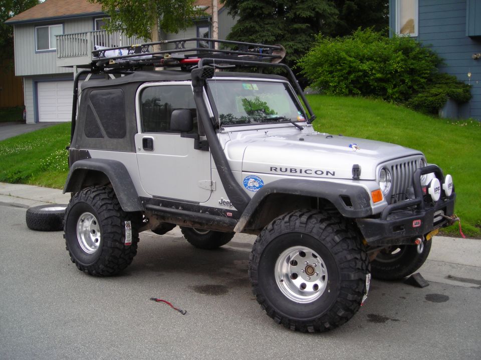 Silver 2003 Jeep TJ Rubicon with snorkel and roof rack parked on street