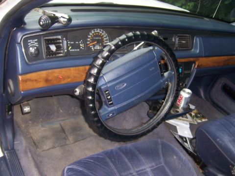 1994 Ford Crown Victoria - The interior of a 1994 Ford Crown Victoria features blue upholstery, wood grain accents on the dashboard, and a Ford steering wheel.