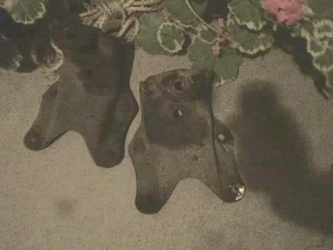 1989 Ford Bronco - Two unidentified metal parts are shown against a carpeted background with floral accents.